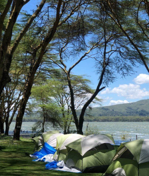 Lakeside view of fishing camps near Lake Naivasha with boats, tents, and scenic natural surroundings.