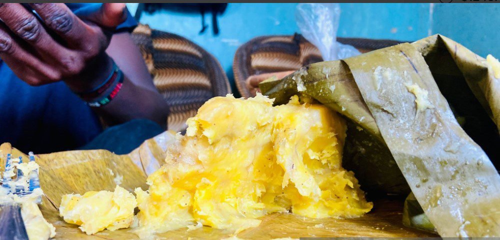Traditional Ugandan matoke dish served with rich groundnut sauce on a banana leaf plate.