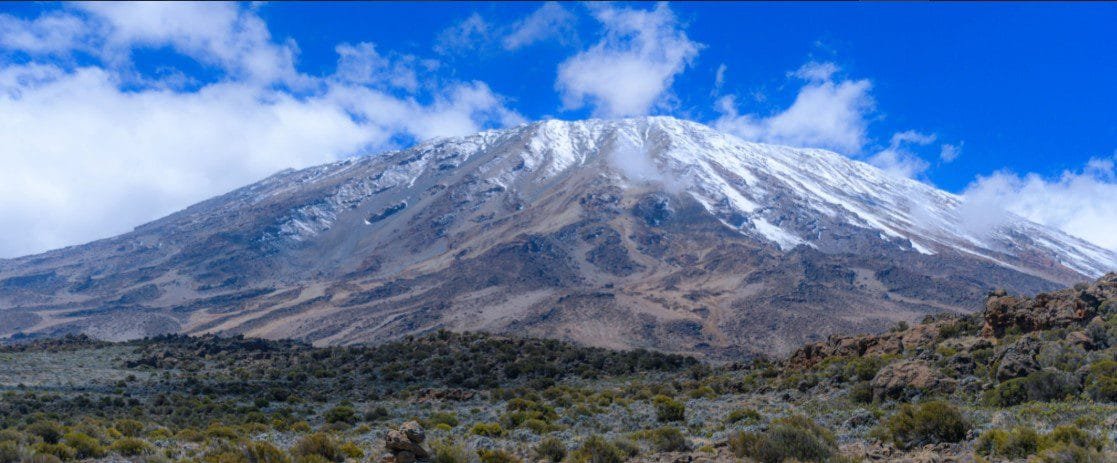 Mount Kilimanjaro towering above the African landscape, with its snow-capped summit and diverse ecosystems.