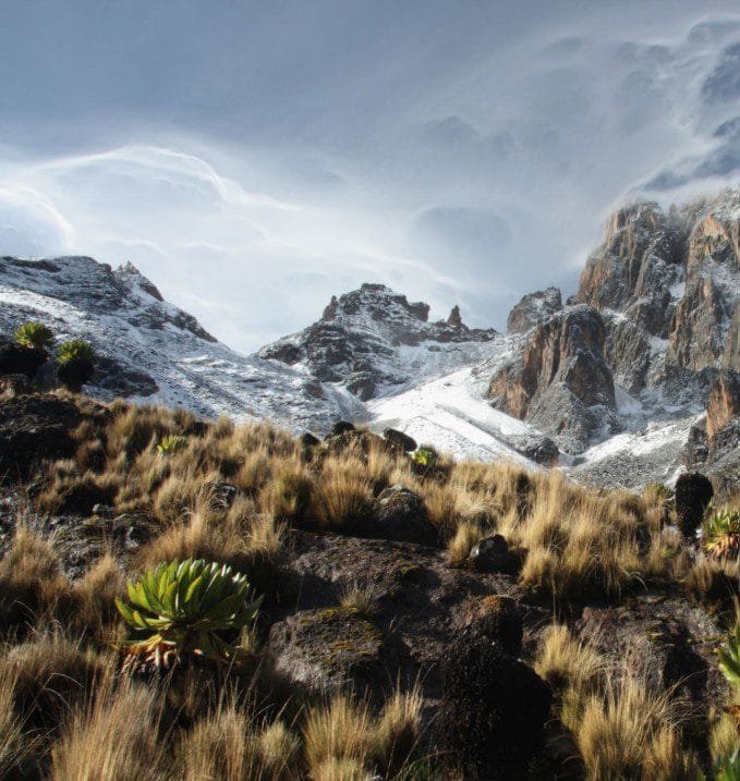 Stunning sunrise over the peaks of Mount Kenya, casting golden light across the rugged landscape."